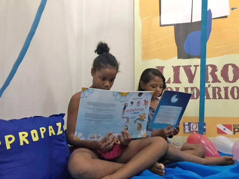 “A leitura me traz sonhos. Fico imaginando as histórias”. As palavras da estudante Luana Campos Ferreira, de 10 anos, foram ditas durante a inauguração do Espaço de Leitura do projeto “Livro Solidário” no polo Pro Paz Ufra (Universidade Federal Rural da Amazônia), nesta quarta-feira, 14, data em que se comemora o Dia do Poeta. Neta de poetisa, Luana gosta de ler gibis e de escrever histórias de terror, suspense e ação. Ela é uma das 322 crianças e adolescentes que moram nos bairros da Terra Firme e Guamá, e que são atendidas no polo. A parceria entre a Imprensa Oficial do Estado (IOE) e o Pro Paz garante mais uma opção de atividade no local, que já oferece opções de esporte e lazer. O evento de inauguração contou com a presença de crianças atendidas no polo, pais e também do poeta Antônio Juraci Siqueira e do ator Eli Chaves que apresentou a performance “O menino e o livro”. As crianças também fizeram leituras de poemas e homenagearam o poeta Juraci Siqueira.
FOTO: ASCOM / IOE
DATA: 14.03.2018
BELÉM - PARÁ <div class='credito_fotos'>Foto: ASCOM IOE | <a href='/midias/2018/originais/0cc63f60-3039-447b-9644-e9a1a08d60ea.jpg' download><i class='fa-solid fa-download'></i> Download</a></div>