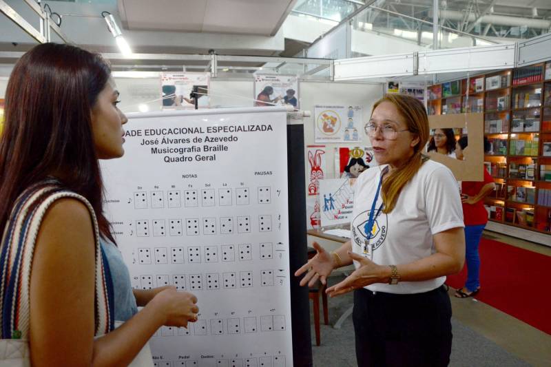 O acesso à leitura da partitura musical por meio das pontas dos dedos para a Pessoa com Deficiência Visual (PcD). É a Musicografia Braille, que esteve em exposição no estande da Secretaria de Estado de Educação (Seduc), nesta segunda-feira, 4, na 22ª Feira do Livro, no Hangar, em Belém. Os técnicos, da Unidade Especializada Álvares de Azevedo da Coordenadoria de Educação Especial (Coees) da Seduc, levaram todas as orientações para o público interessado em conhecer  essa especificidade do Código Braille criado para a escrita e leitura de partituras musicais. Na foto, as professoras de música Tainá Façanha (e) e Rosana Furtado (d).

FOTO: FERNANDO NOBRE / ASCOM SEDUC
DATA: 04.06.2018
BELÉM - PARÁ <div class='credito_fotos'>Foto: FERNANDO NOBRE/ASCOM SEDUC   |   <a href='/midias/2018/originais/0ed8244d-4171-4dcd-bb9c-c74e18bd1f5a.jpg' download><i class='fa-solid fa-download'></i> Download</a></div>