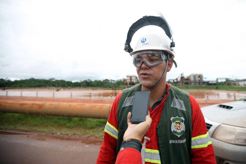 A Secretaria de Estado de Meio Ambiente e Sustentabilidade (Semas) notificou oficialmente a Hydro, na tarde desta terça-feira (27), por conta do não cumprimento do prazo de 48 horas dado pelo governo para que a empresa reduzisse os níveis das bacias de resíduos ao nível de, pelo menos, um metro, conforme determina a legislação ambiental. A notificação foi entregue por técnicos da Semas na sede da refinaria, em Barcarena, a 112 quilômetros de Belém. A determinação é que a produção de alumina seja reduzida pela metade. A Semas também triplicará a multa definida anteriormente, cumprindo a legislação ambiental em vigor, para R$ 1 milhão por dia de descumprimento (ou 300 mil Unidades de Padrão Fiscal). A empresa informou formalmente que reduziu os índices, mas não integralmente no total determinado de um metro. Técnicos das diretorias de Fiscalização e Licenciamento Ambiental da Semas acompanham diariamente o volume de água das bacias, tanto dos depósitos de rejeitos sólidos da indústria quanto do sistema de tratamento de água. Na foto, o fiscal de meio Ambiente Elvis Barreto, da Semas.
FOTO: THIAGO GOMES / AG PARÁ
DATA: 27.02.2018
BARCARENA - PARÁ <div class='credito_fotos'>Foto: Thiago Gomes /Ag. Pará | <a href='/midias/2018/originais/1b23c87f-7bf6-42ec-a545-51674d5e83a9.jpg' download><i class='fa-solid fa-download'></i> Download</a></div>