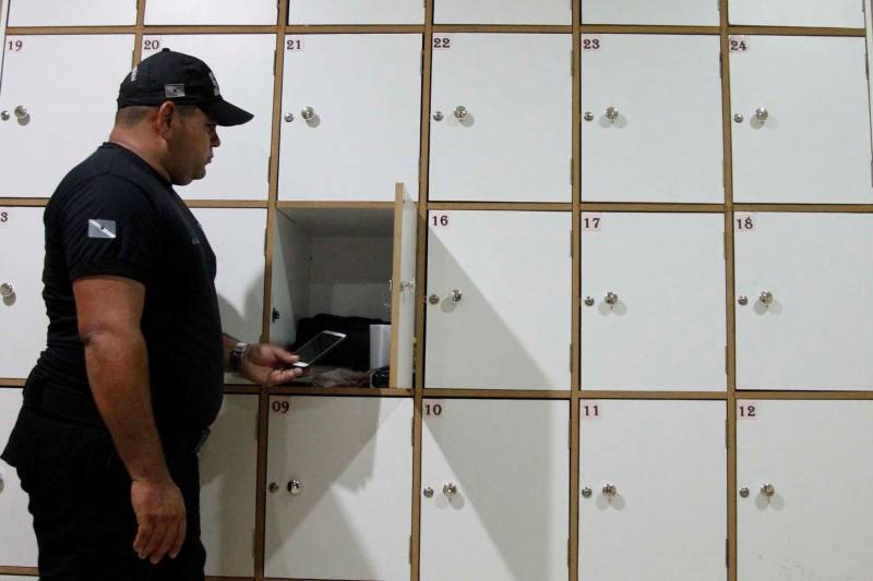 A Superintendência do Sistema Penitenciário do Estado (Susipe) determinou a proibição de uso de celulares por agentes públicos nas unidades prisionais de todo o Estado. A medida tem a finalidade de garantir maior segurança nas unidades penais e impedir a exposição de imagens e vídeos captados no interior das casas penais e o compartilhamento pelas redes sociais, de forma indevida. A Portaria de recomendação Nº 50/2018 entrou em vigor no último dia 26 de janeiro. Os aparelhos dos servidores devem a partir de então ficar guardados nas portarias dos centros de recuperação até o fim do expediente ou plantão. Para a comunicação urgente, os servidores poderão utilizar os telefones fixos e móveis da unidade prisional. Na foto, o agente prisional Elson Mota.
FOTO: AKIRA ONUMA
DATA: 07.02.2018
BELÉM - PARÁ <div class='credito_fotos'>Foto: Akira Onuma / Ascom Susipe | <a href='/midias/2018/originais/2337bf07-325f-47b9-b907-33ad19f5a418.jpg' download><i class='fa-solid fa-download'></i> Download</a></div>