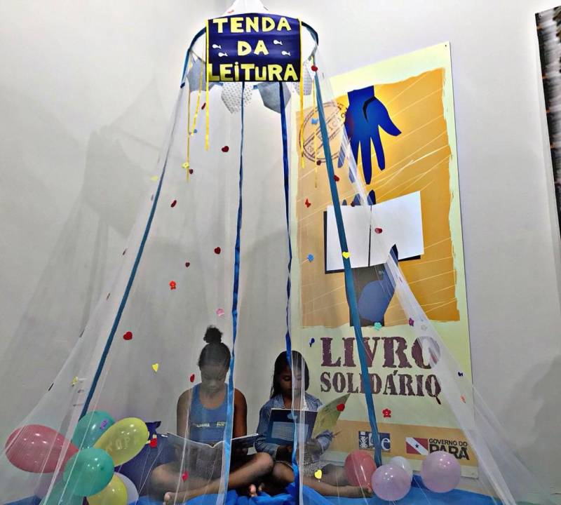 “A leitura me traz sonhos. Fico imaginando as histórias”. As palavras da estudante Luana Campos Ferreira, de 10 anos, foram ditas durante a inauguração do Espaço de Leitura do projeto “Livro Solidário” no polo Pro Paz Ufra (Universidade Federal Rural da Amazônia), nesta quarta-feira, 14, data em que se comemora o Dia do Poeta. Neta de poetisa, Luana gosta de ler gibis e de escrever histórias de terror, suspense e ação. Ela é uma das 322 crianças e adolescentes que moram nos bairros da Terra Firme e Guamá, e que são atendidas no polo. A parceria entre a Imprensa Oficial do Estado (IOE) e o Pro Paz garante mais uma opção de atividade no local, que já oferece opções de esporte e lazer. O evento de inauguração contou com a presença de crianças atendidas no polo, pais e também do poeta Antônio Juraci Siqueira e do ator Eli Chaves que apresentou a performance “O menino e o livro”. As crianças também fizeram leituras de poemas e homenagearam o poeta Juraci Siqueira.
FOTO: ASCOM / IOE
DATA: 14.03.2018
BELÉM - PARÁ <div class='credito_fotos'>Foto: ASCOM IOE | <a href='/midias/2018/originais/2a565f74-9ec3-4e7a-b891-808970d1d0c5.jpg' download><i class='fa-solid fa-download'></i> Download</a></div>