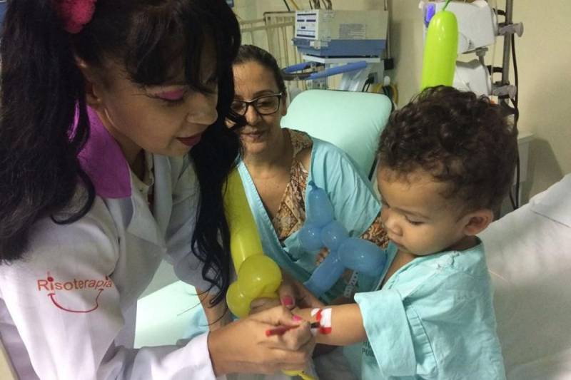 O trabalho voluntário muda a atmosfera hospitalar. O ambiente de dor e apreensão se transforma, e o hospital ganha cores, risos e esperanças. No Hospital Regional do Sudeste do Pará – Dr. Geraldo Veloso (HRSP), localizado em Marabá, vários grupos de voluntariado contribuem com atividades lúdicas para o êxito do tratamento oferecido pelos profissionais da unidade de saúde. Em fevereiro, os grupos “Pipoca e Maionese”, “Amor em Ação”, “Filhos da Caridade” e “Médicos da Alegria” proporcionaram a cada semana alegria e diversão a pacientes de todas as alas do hospital, incluindo a Unidade de Terapia Intensiva (UTI). Para o ajudante de pedreiro José Lira, 25 anos, a presença dos voluntários do grupo “Pipoca e Maionese” foi fundamental na recuperação de seu filho, de 06 anos, internado na UTI Pediátrica. “Antes de começar a brincadeira, meu filho estava chorando, triste, chamando pela mãe. Mas depois ele ficou alegre, pediu até para tomar banho. Eles se divertem. A gente vê que quando começa a brincadeira, eles já ficam alegres, sorrindo”, contou José Lira. Na foto, a voluntária Joelma Lobato Barata, responsável pelo personagem “Tia Pipoca”.
FOTO: ASCOM / HRSP
DATA:27.02.2018
MARABÁ - PARÁ <div class='credito_fotos'>Foto: ASCOM HRSP | <a href='/midias/2018/originais/31263fac-d9ea-4e9e-86d3-297394569061.jpg' download><i class='fa-solid fa-download'></i> Download</a></div>
