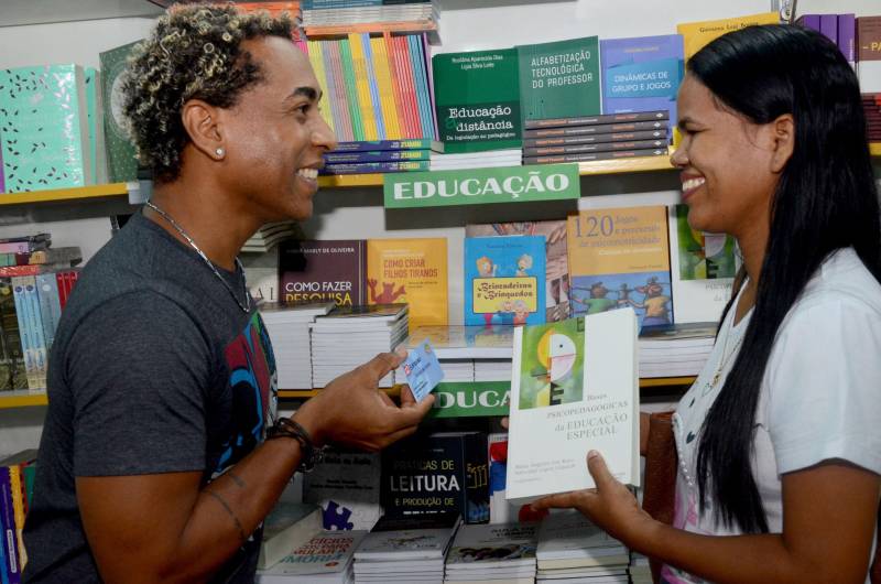 Os professores da Escola Estadual Agostinho Moraes acordaram mais cedo para participar da 22ª edição da Feira Pan-Amazônica do Livro, uma das maiores do Brasil. Incentivados pelo programa Credlivro, que beneficia servidores da rede pública de ensino com bônus destinado à aquisição de livros, a caravana partiu do município de Inhangapi, no nordeste paraense e chegou à convenção literária com o objetivo de aumentar o acervo de material didático e inspirações que podem auxiliar dentro de sala de aula. “Desde que ganhamos o auxílio, passei a comprar mais livros. Tanto para minha sala de aula quanto para a minha filha, que está na fase de alfabetização, porque busco incentivá-la à leitura”, conta a professora de matemática, Denize Batista. A servidora trouxe a filha Alicia, de 3 anos, para aproveitar o espaço dedicado ao livro. Segundo os dados apresentados pela Secretária de Estado de Educação (Seduc), em 2017, aproximadamente 70% dos professores usaram o Credlivro em suas compras. Na foto, a professora de matemática, Denize Batista (d).
FOTO: EUNICE PINTO
DATA: 08.06.2018
BELÉM - PARÁ <div class='credito_fotos'>Foto: Eunice Pinto / Divulgação | <a href='/midias/2018/originais/337640f1-ef8e-4280-904b-f1cf7066ce5e.jpg' download><i class='fa-solid fa-download'></i> Download</a></div>
