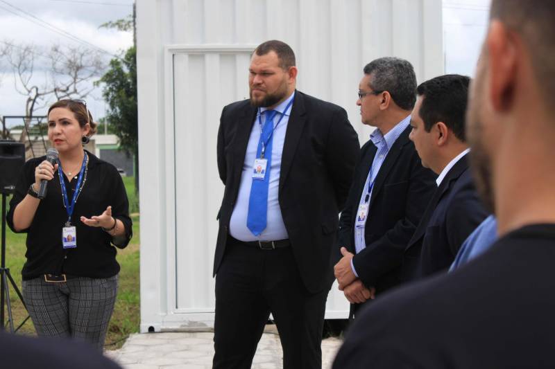 A Superintendência do Sistema Penitenciário do Estado (Susipe) inaugurou, nesta terça-feira (18), no Complexo Penitenciário de Santa Izabel, um espaço com seis salas de vídeo audiência que vão funcionar dentro de um contêiner de 30 m², totalmente reformado e adaptado. Cada sala está equipada com central de ar condicionado, televisão conectada ao equipamento de videoconferência (câmera e microfone), duas cadeiras e câmera de segurança. Todas as salas estão conectadas diretamente com o Tribunal de Justiça do Pará via cabos de fibra óptica, com um link dedicado com velocidade de 100 megas. O investimento foi de mais de R$ 1 milhão de reais, dos recursos do Fundo Penitenciário Nacional. Em 2018, a Susipe recebeu 12.300 pedidos de audiências, só que 12% não foram atendidos, principalmente por dificuldades de logística e escolta. Para o superintendente da Susipe, Michell Durans, o novo espaço terá um impacto muito grande na redução de custos com transporte e agilidade das audiências. Na foto, a coordenadora de procedimentos de custódia da Susipe, Waléria Albuquerque (ao microfone).

FOTO: VELOSO JÚNIOR / ASCOM SUSIPE
DATA: 18.12.2018
SANTA IZABEL - PARÁ <div class='credito_fotos'>Foto: Veloso Junior / Ascom Susipe   |   <a href='/midias/2018/originais/57bdc34f-4706-481b-b048-54b94a79e0eb.jpg' download><i class='fa-solid fa-download'></i> Download</a></div>