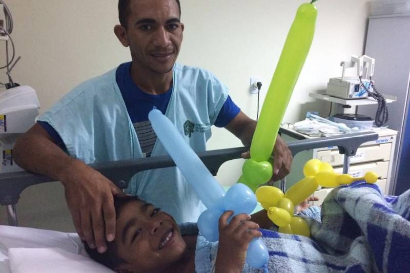 O trabalho voluntário muda a atmosfera hospitalar. O ambiente de dor e apreensão se transforma, e o hospital ganha cores, risos e esperanças. No Hospital Regional do Sudeste do Pará – Dr. Geraldo Veloso (HRSP), localizado em Marabá, vários grupos de voluntariado contribuem com atividades lúdicas para o êxito do tratamento oferecido pelos profissionais da unidade de saúde. Em fevereiro, os grupos “Pipoca e Maionese”, “Amor em Ação”, “Filhos da Caridade” e “Médicos da Alegria” proporcionaram a cada semana alegria e diversão a pacientes de todas as alas do hospital, incluindo a Unidade de Terapia Intensiva (UTI). Para o ajudante de pedreiro José Lira (foto), 25 anos, a presença dos voluntários do grupo “Pipoca e Maionese” foi fundamental na recuperação de seu filho, de 06 anos, internado na UTI Pediátrica. “Antes de começar a brincadeira, meu filho estava chorando, triste, chamando pela mãe. Mas depois ele ficou alegre, pediu até para tomar banho. Eles se divertem. A gente vê que quando começa a brincadeira, eles já ficam alegres, sorrindo”, contou José Lira.
FOTO: ASCOM / HRSP
DATA:27.02.2018
MARABÁ - PARÁ <div class='credito_fotos'>Foto: ASCOM HRSP | <a href='/midias/2018/originais/5d95f00f-8eb3-4fcb-b524-7e839a2de9a0.jpg' download><i class='fa-solid fa-download'></i> Download</a></div>