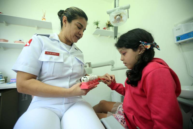 A pequena Ana Sophia, 7 anos (foto), ouve atentamente às instruções da major odontóloga Lilianne Oliveira de como escovar corretamente os dentes. Ao lado, a mãe, a cabo Isabela Lima, integrante do Corpo de Bombeiros Militar do Pará há 11 anos, comemora a oportunidade de levar seus filhos ao dentista sem precisar se ausentar do trabalho.
FOTO: THIAGO GOMES / AG. PARÁ
DATA: 13.04.2018
BELÉM - PARÁ
<div class='credito_fotos'>Foto: Thiago Gomes /Ag. Pará | <a href='/midias/2018/originais/65dca389-47bd-4cee-ba90-b7c9f1f7b5de.jpg' download><i class='fa-solid fa-download'></i> Download</a></div>