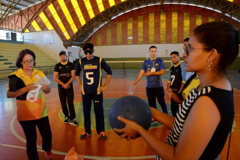 A Secretaria de Estado de Educação (Seduc), por meio do Núcleo de Esporte e Lazer (NEL), promove oficinas de capacitação destinada a professores e técnicos das escolas dos municípios participantes da XI edição dos Jogos Paralímpicos Escolares Paraenses, visando destacar a importância do incentivo à prática de esportes por pessoas com deficiência (PcD). As oficinas ocorrem paralelamente à competição, que será encerrada nesta sexta-feira (29), em Marabá, no sudeste do Estado, com disputas nas modalidades atletismo, bocha e natação. No Ginásio Renato Veloso ocorreu a oficina de goaball, único esporte criado exclusivamente para deficientes visuais. A modalidade esportiva, que foi implantada de forma pioneira no Estado para ser praticado por estudantes da Unidade de Ensino Especializada Álvares de Azevedo, está sendo levada a outros municípios paraenses. Na foto, a oficina de goaball foi ministrada pela professora Kátia Tadaisky Lima (óculos e camisa amarela), da Unidade Especializada Álvares de Azevedo.
FOTO: FERNANDO NOBRE / ASCOM SEDUC
DATA: 29.06.2018
MARABÁ - PARÁ <div class='credito_fotos'>Foto: FERNANDO NOBRE/ASCOM SEDUC | <a href='/midias/2018/originais/6ed51fac-d036-414a-9b67-a09994aed93a.jpg' download><i class='fa-solid fa-download'></i> Download</a></div>