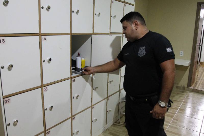 A Superintendência do Sistema Penitenciário do Estado (Susipe) determinou a proibição de uso de celulares por agentes públicos nas unidades prisionais de todo o Estado. A medida tem a finalidade de garantir maior segurança nas unidades penais e impedir a exposição de imagens e vídeos captados no interior das casas penais e o compartilhamento pelas redes sociais, de forma indevida. A Portaria de recomendação Nº 50/2018 entrou em vigor no último dia 26 de janeiro. Os aparelhos dos servidores devem a partir de então ficar guardados nas portarias dos centros de recuperação até o fim do expediente ou plantão. Para a comunicação urgente, os servidores poderão utilizar os telefones fixos e móveis da unidade prisional. Na foto, o agente prisional Elson Mota.
FOTO: AKIRA ONUMA
DATA: 07.02.2018
BELÉM - PARÁ <div class='credito_fotos'>Foto: Akira Onuma / Ascom Susipe | <a href='/midias/2018/originais/6fe78af6-1efa-4648-9ae0-e02fc09789e1.jpg' download><i class='fa-solid fa-download'></i> Download</a></div>