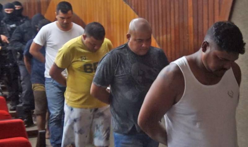 As Polícias Civil e Militar apresentaram, nesta terça-feira (29), em entrevista coletiva na Delegacia Geral, em Belém, informações sobre as prisões de oito pessoas (foto), entre elas dois policiais militares e um guarda municipal, por envolvimento na tentativa de furto mediante arrombamento de uma agência bancária, no município de Benevides. As prisões em flagrante foram realizadas por policiais militares, na madrugada de segunda-feira (28), por volta de 3 horas, em uma barreira policial, na rodovia BR-316, município de Marituba. Os presos foram conduzidos à Divisão de Repressão ao Crime Organizado (DRCO), onde foram autuados pelos crimes de associação criminosa, tentativa de furto qualificado, porte ilegal de arma de fogo e uso de documento falso. Com os presos, foram apreendidos materiais usados em arrombamentos e em corte de cofres e caixas eletrônicos, como cilindro de oxigênio, botijão de gás e mangueira usados em maçarico, além de ferramentas como furadeira e serra elétrica, colete balístico, luvas, máscara de oxigênio, entre outros equipamentos.
FOTO: ASCOM / POLÍCIA CIVIL
DATA: 29.05.2018
BELÉM - PARÁ <div class='credito_fotos'>Foto: Ascom / Polícia Civil | <a href='/midias/2018/originais/76a958bc-1948-4d09-95ef-e5240eee1c3e.jpg' download><i class='fa-solid fa-download'></i> Download</a></div>