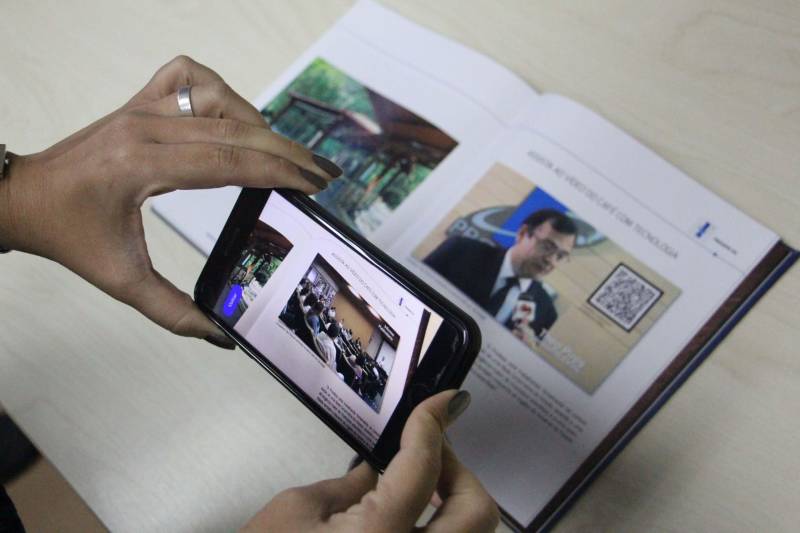 Se você achava que objetos pulando para fora da tela era coisa de filme de ficção científica, está na hora de rever seus conceitos. Aliás, o que acontece com a Realidade Aumentada (foto) é o contrário: você pula para dentro do mundo virtual para interagir com uma nova dimensão no modo como executamos tarefas. Essa tecnologia já está disponível no Prodepa RA, o software de Realidade Aumentada desenvolvido pela Empresa de Tecnologia da Informação e Comunicação do Estado do Pará (Prodepa). Hitoshi Seki, assessor da Prodepa, explica que Realidade Aumentada é uma tecnologia que permite que o mundo virtual seja misturado ao real, possibilitando maior interação. “O aplicativo lembra muito cenas do filme Harry Potter, quando mostrava um jornal e a imagem do jornal era animada, como se ela estivesse viva. O Prodepa RA faz isso também, só que através da tela do celular. Aponta-se o celular para uma imagem e essa imagem vai virar um vídeo, uma imagem em alta resolução ou até um áudio”.

FOTO: ASCOM / PRODEPA
DATA: 12.12.2018
BELÉM - PARÁ <div class='credito_fotos'>Foto: Ascom Prodepa   |   <a href='/midias/2018/originais/7c14f3ab-14e4-45a1-9a0c-e881eb4f0495.jpg' download><i class='fa-solid fa-download'></i> Download</a></div>