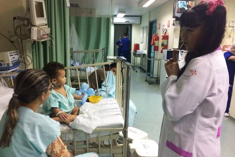 O trabalho voluntário muda a atmosfera hospitalar. O ambiente de dor e apreensão se transforma, e o hospital ganha cores, risos e esperanças. No Hospital Regional do Sudeste do Pará – Dr. Geraldo Veloso (HRSP), localizado em Marabá, vários grupos de voluntariado contribuem com atividades lúdicas para o êxito do tratamento oferecido pelos profissionais da unidade de saúde. Em fevereiro, os grupos “Pipoca e Maionese”, “Amor em Ação”, “Filhos da Caridade” e “Médicos da Alegria” proporcionaram a cada semana alegria e diversão a pacientes de todas as alas do hospital, incluindo a Unidade de Terapia Intensiva (UTI). Para o ajudante de pedreiro José Lira, 25 anos, a presença dos voluntários do grupo “Pipoca e Maionese” foi fundamental na recuperação de seu filho, de 06 anos, internado na UTI Pediátrica. “Antes de começar a brincadeira, meu filho estava chorando, triste, chamando pela mãe. Mas depois ele ficou alegre, pediu até para tomar banho. Eles se divertem. A gente vê que quando começa a brincadeira, eles já ficam alegres, sorrindo”, contou José Lira. Na foto, a voluntária Joelma Lobato Barata, responsável pelo personagem “Tia Pipoca”.
FOTO: ASCOM / HRSP
DATA:27.02.2018
MARABÁ - PARÁ <div class='credito_fotos'>Foto: ASCOM HRSP | <a href='/midias/2018/originais/89199de4-3b7a-4332-87dd-b3d3d045d68e.jpg' download><i class='fa-solid fa-download'></i> Download</a></div>