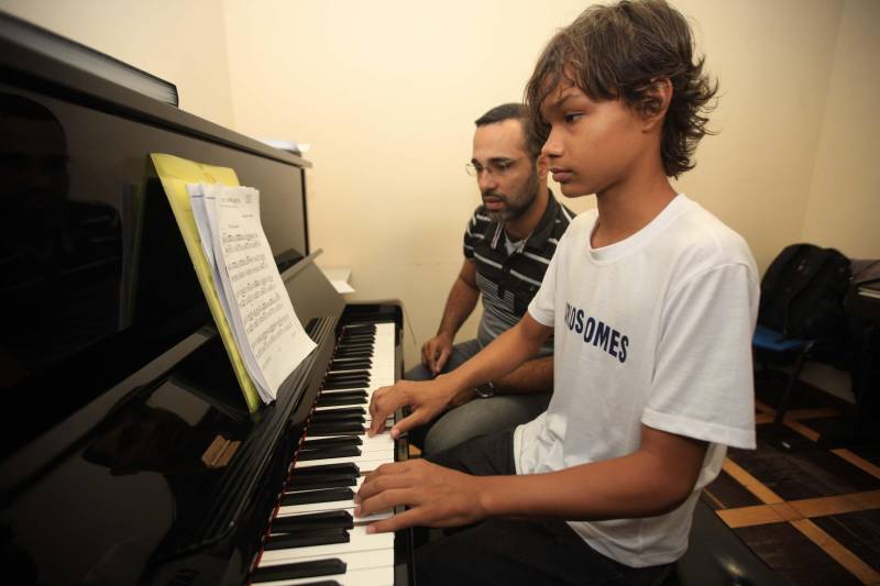 No próximo mês de junho acontece o Festival Internacional de Música do Pará, principal evento artístico da Fundação Carlos Gomes, chega a sua 31ª edição em 2018. O evento integra o calendário de ações do Governo do Pará voltadas para a promoção da cultura trazendo a Belém grandes nomes da música erudita nacional e internacional, bem como artistas consagrados da Música Popular Brasileira, além de músicos que se destacam na cena instrumental. A música já transformou a vida de muitos alunos que passam pela Instituição. O diretor de ensino da Fundação, Claudio Trindade explica que os estudantes da Fundação Carlos Gomes são oriundos de todos os níveis sociais, de escolas publicas e de escolas particulares, alunos que vem de famílias tradicionais na música, alunos oriundos de projetos sociais, de igrejas, este último um percentual muito grande, pois a religião oferece um ambiente propício ao desenvolvimento da musica Há também alunos oriundos do interior do Estado. Na foto, João Paulo Baena (camisa branca), 12 anos, e seu pai, o servidor público Paulo Robson Baena, 34 anos.
FOTO: CARLOS SODRÉ / AG. PARÁ
DATA: 25.04.2018
BELÉM - PARÁ <div class='credito_fotos'>Foto: Carlos Sodré/Agência Pará | <a href='/midias/2018/originais/b35fbcc6-3615-4761-86be-4a7d71f4ef72.jpg' download><i class='fa-solid fa-download'></i> Download</a></div>