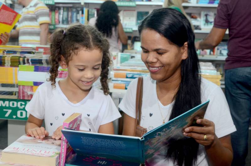 Os professores da Escola Estadual Agostinho Moraes acordaram mais cedo para participar da 22ª edição da Feira Pan-Amazônica do Livro, uma das maiores do Brasil. Incentivados pelo programa Credlivro, que beneficia servidores da rede pública de ensino com bônus destinado à aquisição de livros, a caravana partiu do município de Inhangapi, no nordeste paraense e chegou à convenção literária com o objetivo de aumentar o acervo de material didático e inspirações que podem auxiliar dentro de sala de aula. “Desde que ganhamos o auxílio, passei a comprar mais livros. Tanto para minha sala de aula quanto para a minha filha, que está na fase de alfabetização, porque busco incentivá-la à leitura”, conta a professora de matemática, Denize Batista. A servidora trouxe a filha Alicia, de 3 anos, para aproveitar o espaço dedicado ao livro. Segundo os dados apresentados pela Secretária de Estado de Educação (Seduc), em 2017, aproximadamente 70% dos professores usaram o Credlivro em suas compras. Na foto, a professora de matemática, Denize Batista (d) com a filha, Alicia (e).
FOTO: EUNICE PINTO
DATA: 08.06.2018
BELÉM - PARÁ <div class='credito_fotos'>Foto: Eunice Pinto / Divulgação | <a href='/midias/2018/originais/cb19ce42-4ea0-4a71-b0ca-3e825dda5f38.jpg' download><i class='fa-solid fa-download'></i> Download</a></div>