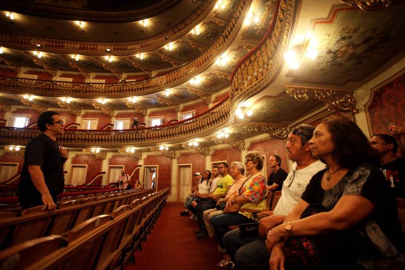 O aposentado Mário Printes, 74 anos, tem o costume de visitar o Theatro da Paz pelo menos uma vez ao mês. É apaixonado pela arquitetura e história do lugar e, se instigado, é capaz de falar horas sobre ele. Nesta quinta-feira (15), dia no qual o espaço completa 140 anos, o aposentado estava na fila para retirar o ingresso do concerto da Amazônia Jazz Band, que marcará, nesta mesma noite, o aniversário do prédio centenário. “Não poderia ficar de fora dessa programação. Seria como não prestigiar um amigo próximo e querido no dia do seu aniversário”, disse Mário. Com a regência do maestro Nelson Neves e a cantora Simone Almeida como convidada especial, o concerto “Celebrando Theatro da Paz e Waldemar Henrique” comemora o aniversário de 140 anos do teatro e 113 anos do maestro paraense – que nasceu na mesma data de fundação da casa. A entrada é gratuita e o espetáculo começa às 20 horas.
FOTO: SIDNEY OLIVEIRA / AG PARÁ
DATA: 15.02.2018
BELÉM - PARÁ <div class='credito_fotos'>Foto: Sidney Oliveira/Ag. Pará | <a href='/midias/2018/originais/cd9bb1b9-a8a8-439b-b947-3b03999dd2c3.jpg' download><i class='fa-solid fa-download'></i> Download</a></div>