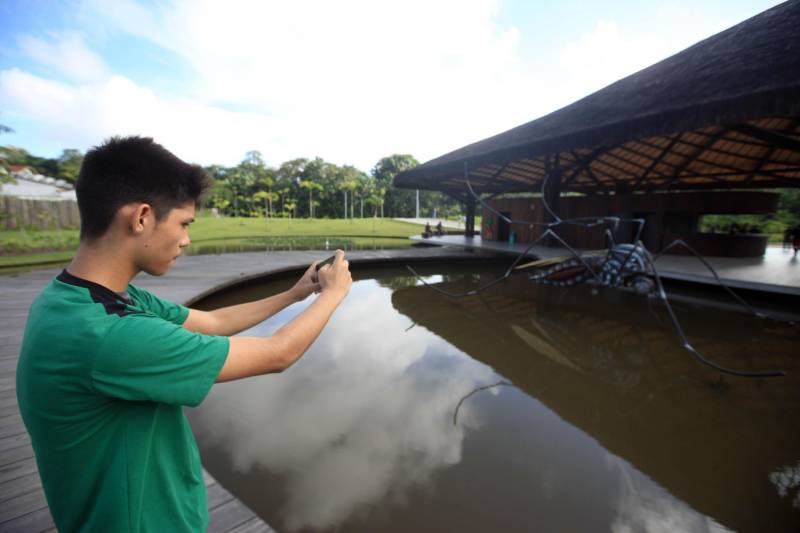Olha, mãe, o mosquito que dá doença. Água parada dá dengue, né?”. Foram essas as palavras da pequena Valentina Marie, de apenas 2 anos e oito meses, ao avistar a escultura em forma de um mosquito, instalada no lago do Parque Estadual do Utinga (Peut). Com a simplicidade genuína das crianças, ela traduziu a proposta de arte educativa da peça que vem virando atração no novo ponto turístico do Estado. Na manhã da última quinta-feira (22), a escultura em fibra de vidro mais uma vez chamou atenção, dessa vez de estudantes das redes municipal e estadual, que participaram da primeira visita técnica ao parque. A visita ao Parque do Utinga fez parte das atividades da V Conferência Nacional Infantojuvenil pelo Meio Ambiente, que este ano trabalha o tema “Vamos cuidar do Brasil cuidando das águas” e vem mobilizando educadores em projetos de educação ambiental. Durante a excursão, os estudantes ouviram sobre a importância do espaço como uma unidade de conservação estadual, criada para preservar ecossistemas e mananciais, como os lagos Bolonha e Água Preta, que abastecem cerca de 70% da população de Belém. Na foto, o estudante Ruan Victor, 14 anos, aluno da Escola Municipal Parque Amazonas, na Terra Firme.
FOTO: SIDNEY OLIVEIRA / AG. PARÁ
DATA: 23.03.2018
BELÉM - PARÁ <div class='credito_fotos'>Foto: Sidney Oliveira/Ag. Pará | <a href='/midias/2018/originais/d58efd1d-cf70-4263-a794-427d2327e793.jpg' download><i class='fa-solid fa-download'></i> Download</a></div>