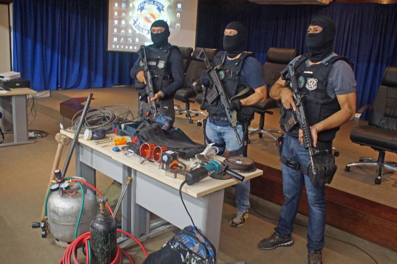 As Polícias Civil e Militar apresentaram, nesta terça-feira (29), em entrevista coletiva na Delegacia Geral, em Belém, informações sobre as prisões de oito pessoas, entre elas dois policiais militares e um guarda municipal, por envolvimento na tentativa de furto mediante arrombamento de uma agência bancária, no município de Benevides. As prisões em flagrante foram realizadas por policiais militares, na madrugada de segunda-feira (28), por volta de 3 horas, em uma barreira policial, na rodovia BR-316, município de Marituba. Os presos foram conduzidos à Divisão de Repressão ao Crime Organizado (DRCO), onde foram autuados pelos crimes de associação criminosa, tentativa de furto qualificado, porte ilegal de arma de fogo e uso de documento falso. Com os presos, foram apreendidos materiais (foto) usados em arrombamentos e em corte de cofres e caixas eletrônicos, como cilindro de oxigênio, botijão de gás e mangueira usados em maçarico, além de ferramentas como furadeira e serra elétrica, colete balístico, luvas, máscara de oxigênio, entre outros equipamentos.
FOTO: ASCOM / POLÍCIA CIVIL
DATA: 29.05.2018
BELÉM - PARÁ <div class='credito_fotos'>Foto: Ascom / Polícia Civil | <a href='/midias/2018/originais/dfb0d5fc-7bfb-4512-99c4-5e36192a2c32.jpg' download><i class='fa-solid fa-download'></i> Download</a></div>