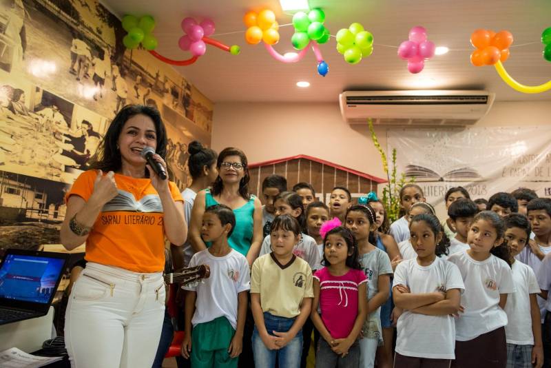 “A cultura tem o poder de emocionar”. A frase dita pela professora Ruth Valin marcou o tom do Sarau Literário na manhã desta sexta-feira, 8, no Preventório Santa Terezinha, no bairro do Marco, em Belém, que contou com a presença do escritor paraense Daniel Leite, homenageado pelas crianças atendidas pela instituição e os alunos da Escola Estadual Santa Terezinha, que funciona no mesmo prédio. Elas cantaram músicas infantis e recitaram trechos das obras “A história das crianças que plantaram um rio” e “A menina árvore”, de Daniel Leite, além de apresentar uma dramatização sobre a primeira obra. Muito concentrados e com a leitura bem ensaiada, os pequeninos emocionaram a todos, principalmente o escritor convidado para o sarau. Segundo a professora Odinéia Bastos, que orientou os alunos na leitura do livro “A história das crianças que plantaram um rio”, elas soltaram a imaginação durante a leitura da obra, e dessa viagem saíram desenhos, pinturas, colagens e poemas, que enfeitaram o auditório e os corredores da instituição, encantando a todos os presentes. Na foto, a coordenadora do projeto Livro Solidário, da Imprensa Oficial do Estado, Carmen Palheta.
FOTO: FERNANDO SETTE CÂMARA / ASCOM IOE
DATA: 08.06.2018
BELÉM - PARÁ <div class='credito_fotos'>Foto: FERNANDO SETTE CÂMARA / ASCOM IOE | <a href='/midias/2018/originais/f065b1b6-7e4a-4605-a242-ad4521d5220a.jpg' download><i class='fa-solid fa-download'></i> Download</a></div>