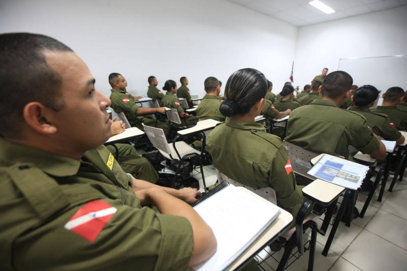 “A sociedade está prestes a receber novos policiais, profissionais prontos e treinados para defender o cidadão. Mesmo ainda não tendo encerrado o curso, já me sinto um PM. A instituição pode ter certeza que estarei sempre de pronto-emprego para atender no que ela precisar de mim”. A fala do aluno do Centro de Formação, dita nesta segunda-feira (7) durante uma aula do Curso de Formação e Aperfeiçoamento de Praças (CFAP) da Polícia Militar do Pará, demonstra o sentimento dos cerca de 2 mil homens e mulheres que estão próximos de encerrar o curso e iniciar seus trabalhos nas ruas. Em Belém, na sede do CFAP, estão em fase de conclusão da formação, cerca de 500 alunos (foto), entre homens e mulheres. Já no interior do Estado, outros 1. 500 passam pelo curso que também acontece nos municípios Conceição do Araguaia, Itaituba, Santarém, Marabá, Parauapebas, Castanhal, Santa Izabel do Pará, Tucuruí, Paragominas, Capanema, Bragança, Altamira, Barcarena, Soure e Breves. A previsão é que no início de agosto deste ano, todos já estejam efetivamente nas ruas. Aprovados no último concurso público da instituição, os futuros policiais estão desde outubro de 2017 participando de um novo modelo formação. De acordo com o major Arthur Silva, sub-comandante do CFAP, a mudança na grade do curso quase dobrou o número de horas aula.
FOTO: RODOLFO OLIVEIRA / AG. PARÁ
DATA: 08.05.2018
BELÉM - PARÁ <div class='credito_fotos'>Foto: Rodolfo Oliveira/Ag. Pará | <a href='/midias/2018/originais/fc5c11bc-efcc-4bf7-9992-d203d4424059.jpg' download><i class='fa-solid fa-download'></i> Download</a></div>