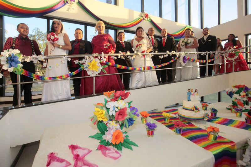 De vestido vermelho, a autónoma Kelly Ferrão, de 40 anos, segurando uma das mãos da noiva, a auxiliar de serviços gerais Suzana Pantoja, 35, não continha nos olhos a emoção pelo que estava por vir. "Chegamos aqui na luta, na raça mesmo. Estar aqui é um desafio vencido", confirmou, minutos antes de participar da 5a edição do Casamento Comunitário Homoafetivo, realizado na tarde desta sexta, 5, no auditório do Instituto de Ciências Jurídicas da Universidade Federal do Para (ICJ-UFPA). Além delas, outros dez casais de homens e mulheres gays, lésbicas, bissexuais e transexuais puderam oficializar, juridicamente, a relação estável, ou aos que queiram, apenas fazer a renovação dos votos. Embora não estivesse lotado, o espaço pareceu, diversas vezes, pequeno para comportar tanta emoção, orgulho e a certeza de que o amor sempre vence.
 <div class='credito_fotos'>Foto: Ricardo Amanajás / Ag. Pará   |   <a href='/midias/2019/originais/2851__j1o0888.jpg' download><i class='fa-solid fa-download'></i> Download</a></div>