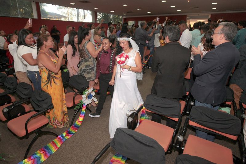 De vestido vermelho, a autónoma Kelly Ferrão, de 40 anos, segurando uma das mãos da noiva, a auxiliar de serviços gerais Suzana Pantoja, 35, não continha nos olhos a emoção pelo que estava por vir. "Chegamos aqui na luta, na raça mesmo. Estar aqui é um desafio vencido", confirmou, minutos antes de participar da 5a edição do Casamento Comunitário Homoafetivo, realizado na tarde desta sexta, 5, no auditório do Instituto de Ciências Jurídicas da Universidade Federal do Para (ICJ-UFPA). Além delas, outros dez casais de homens e mulheres gays, lésbicas, bissexuais e transexuais puderam oficializar, juridicamente, a relação estável, ou aos que queiram, apenas fazer a renovação dos votos. Embora não estivesse lotado, o espaço pareceu, diversas vezes, pequeno para comportar tanta emoção, orgulho e a certeza de que o amor sempre vence.
 <div class='credito_fotos'>Foto: Ricardo Amanajás / Ag. Pará   |   <a href='/midias/2019/originais/2851__j1o0906.jpg' download><i class='fa-solid fa-download'></i> Download</a></div>
