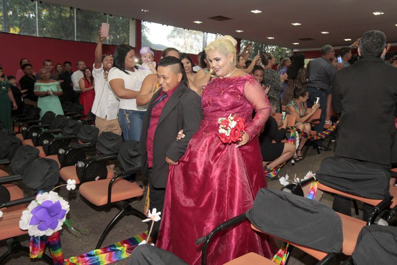 De vestido vermelho, a autónoma Kelly Ferrão, de 40 anos, segurando uma das mãos da noiva, a auxiliar de serviços gerais Suzana Pantoja, 35, não continha nos olhos a emoção pelo que estava por vir. "Chegamos aqui na luta, na raça mesmo. Estar aqui é um desafio vencido", confirmou, minutos antes de participar da 5a edição do Casamento Comunitário Homoafetivo, realizado na tarde desta sexta, 5, no auditório do Instituto de Ciências Jurídicas da Universidade Federal do Para (ICJ-UFPA). Além delas, outros dez casais de homens e mulheres gays, lésbicas, bissexuais e transexuais puderam oficializar, juridicamente, a relação estável, ou aos que queiram, apenas fazer a renovação dos votos. Embora não estivesse lotado, o espaço pareceu, diversas vezes, pequeno para comportar tanta emoção, orgulho e a certeza de que o amor sempre vence.
 <div class='credito_fotos'>Foto: Ricardo Amanajás / Ag. Pará   |   <a href='/midias/2019/originais/2851__j1o0907.jpg' download><i class='fa-solid fa-download'></i> Download</a></div>