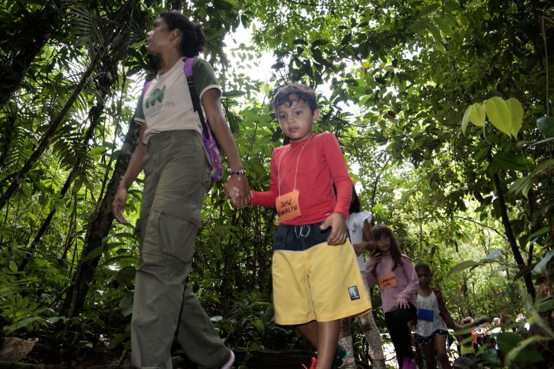As instruções do condutor Diego Neres eram muito claras: – Não pode arrancar folha das árvores; não pode pegar nenhum bichinho que passar por vocês; não pode jogar lixo no chão. As informações foram repassadas a 25 crianças que olhavam atentas e animadas para o instrutor, que trabalha com esporte de aventuras há quatro anos e, especificamente, com crianças, há três. Em seguida, todos iniciaram uma trilha no Parque Estadual do Utinga (PEUT), onde é realizada a Colônia de Férias, sob o comando da equipe do Amazônia Ventura. <div class='credito_fotos'>Foto: Jader Paes / Agência Pará   |   <a href='/midias/2019/originais/2924__v5o1041.jpg' download><i class='fa-solid fa-download'></i> Download</a></div>