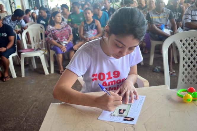 Após sete anos sem documento de identidade, Alice Valente (foto), de 22 anos, aproveitou a ação de cidadania, prevenção e segurança realizada pela Secretaria de Estado de Segurança Pública e Defesa Social (Segup) por meio da Diretoria de Prevenção Social da Violência e Criminalidade (Diprev), para tirar o novo documento. Sem o RG ela conta que teve muitas dificuldades. “Eu não consegui abrir conta em banco, alguns atendimentos eu não conseguia, pois não aceitavam minha carteira de trabalho e agora vai melhorar muito. Eu já vinha tentando tirar meu RG até em outros bairros mais longe e não tive sucesso, até porque com a gestação fiquei sem tempo”, afirmou Alice que também recebeu atendimento pediátrico para a filha. A ação visa garantir serviços para a população e o diálogo junto aos órgãos de Segurança. O encontro oportuniza, ainda, o debate dos problemas que rondam as comunidades, assim como traçar medidas de prevenção, a fim de reduzir a criminalidade

FOTO: ELIELSON MODESTO / ASCOM SEGUP
DATA: 05.01.2019
 <div class='credito_fotos'>Foto: Elielson Modesto / Ascom Segup   |   <a href='/midias/2019/originais/823172fe-4dd1-4c13-a794-407d6b7f4768.jpg' download><i class='fa-solid fa-download'></i> Download</a></div>
