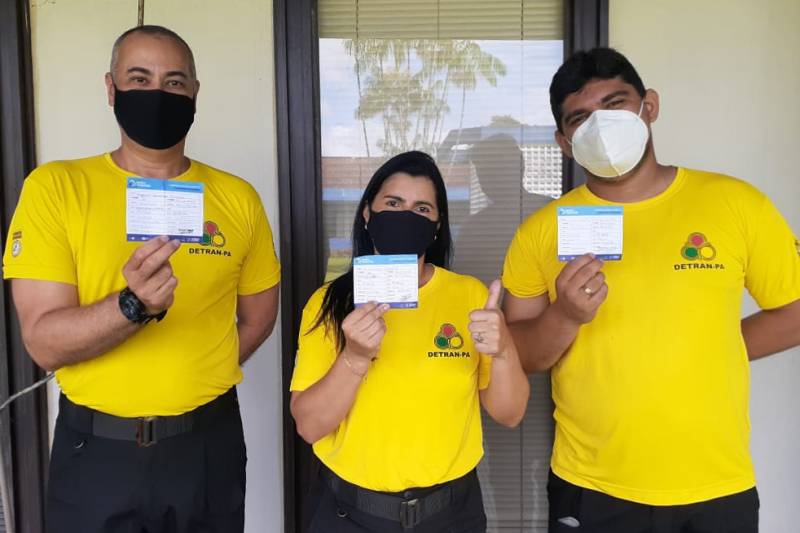 Agentes do Detran mostram aliviados a carteira de vacinação contra a Covid-19