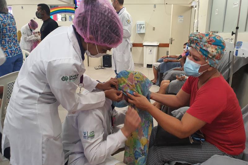 Paciente Suelem aprendendo a colocar o lenço em um voluntário.