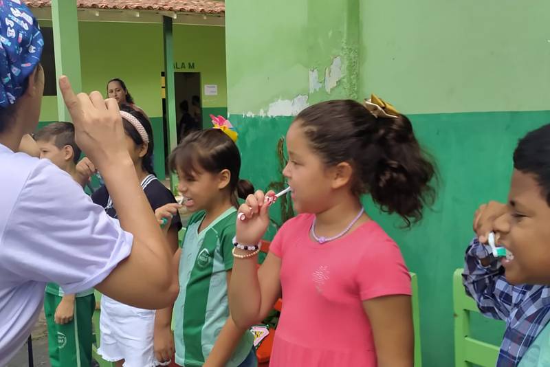 A odontóloga Isabelle Alves  faz profilaxia e orienta crianças sobre escovação dos dentes.