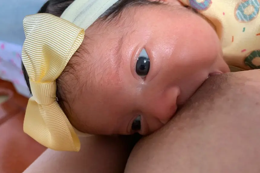 Laura Vitória, alguns dias depois da alta, tomando leite da mãe